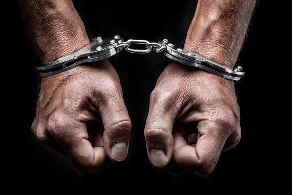 Handcuffs on a man's hands on black background.