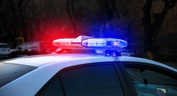 A police car in the street with red and blue lights flashing.